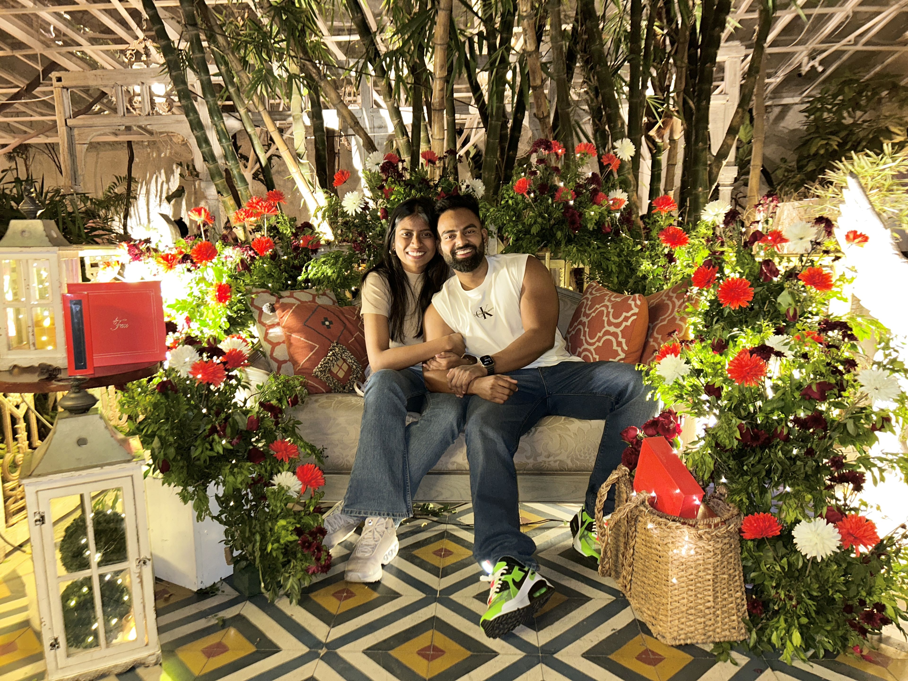 Rhea & Joshua sitting together beneath flowers